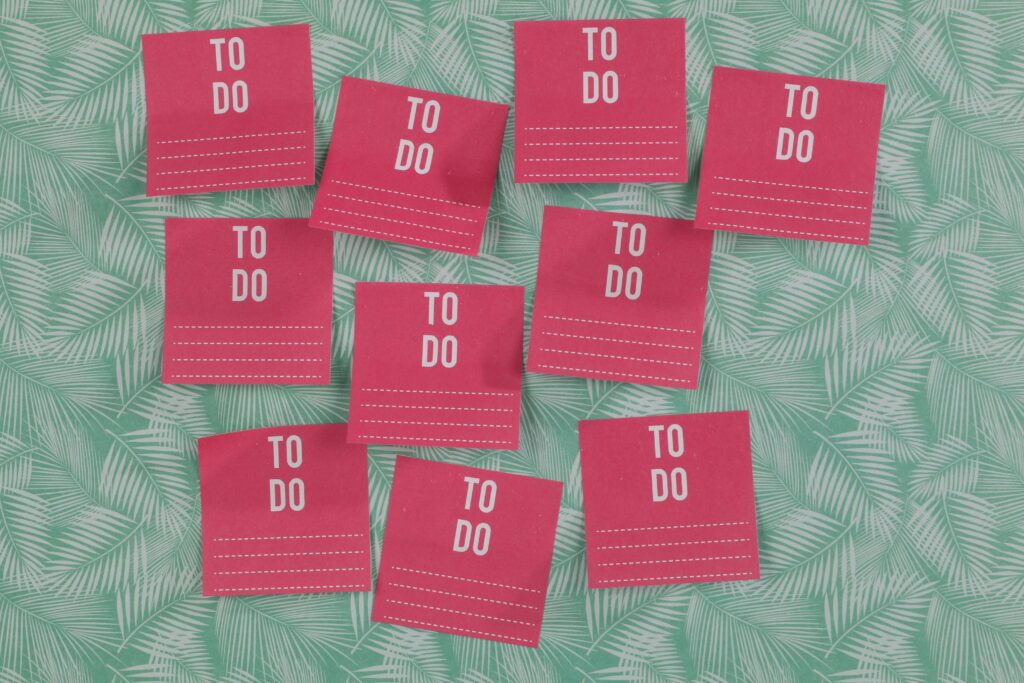 Bright pink to-do list notes arranged on a green leafy patterned background, creating an organized and vibrant workspace vibe.